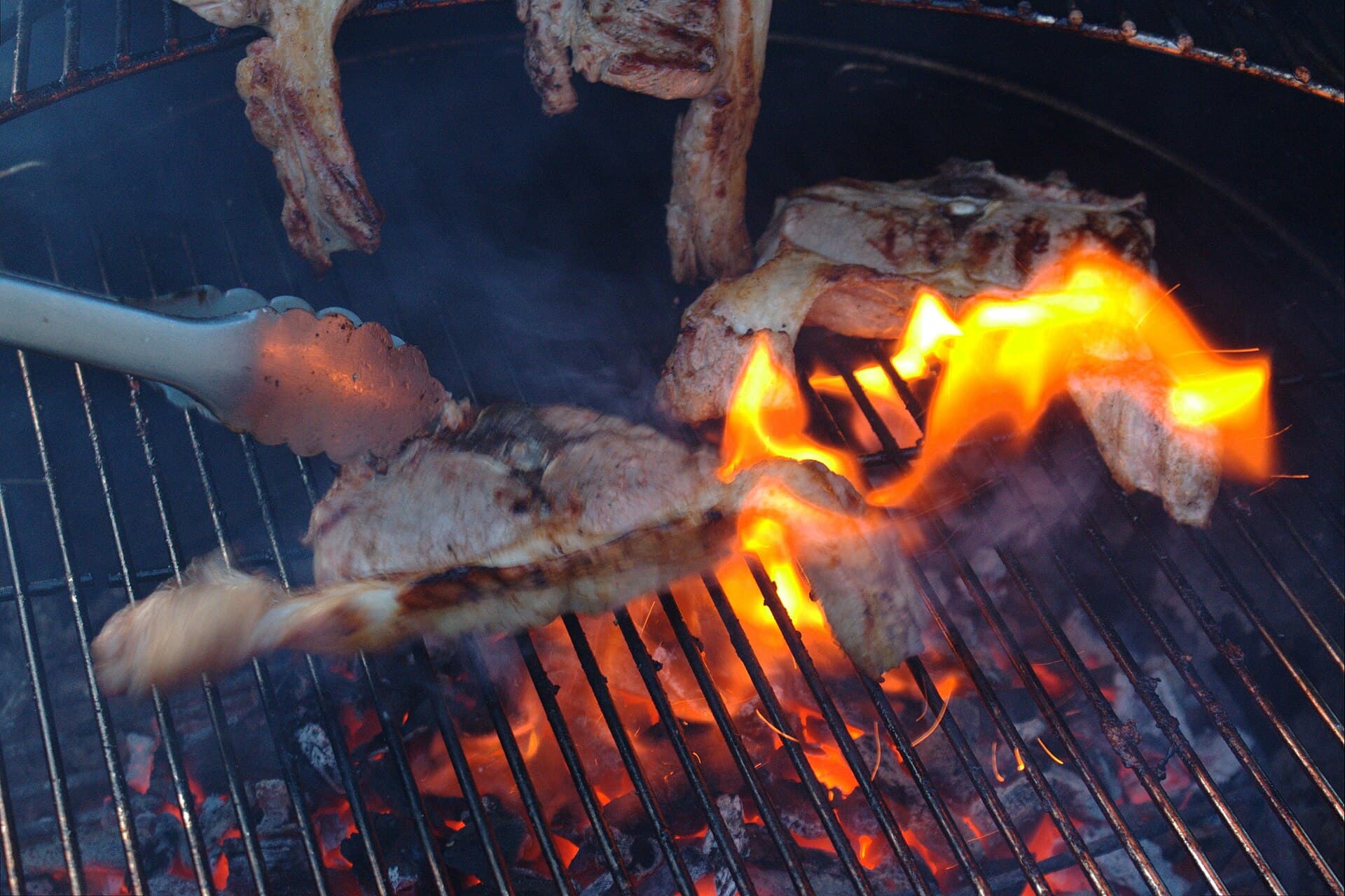 Lamb chops cooking on a barbecue grate over glowing heat