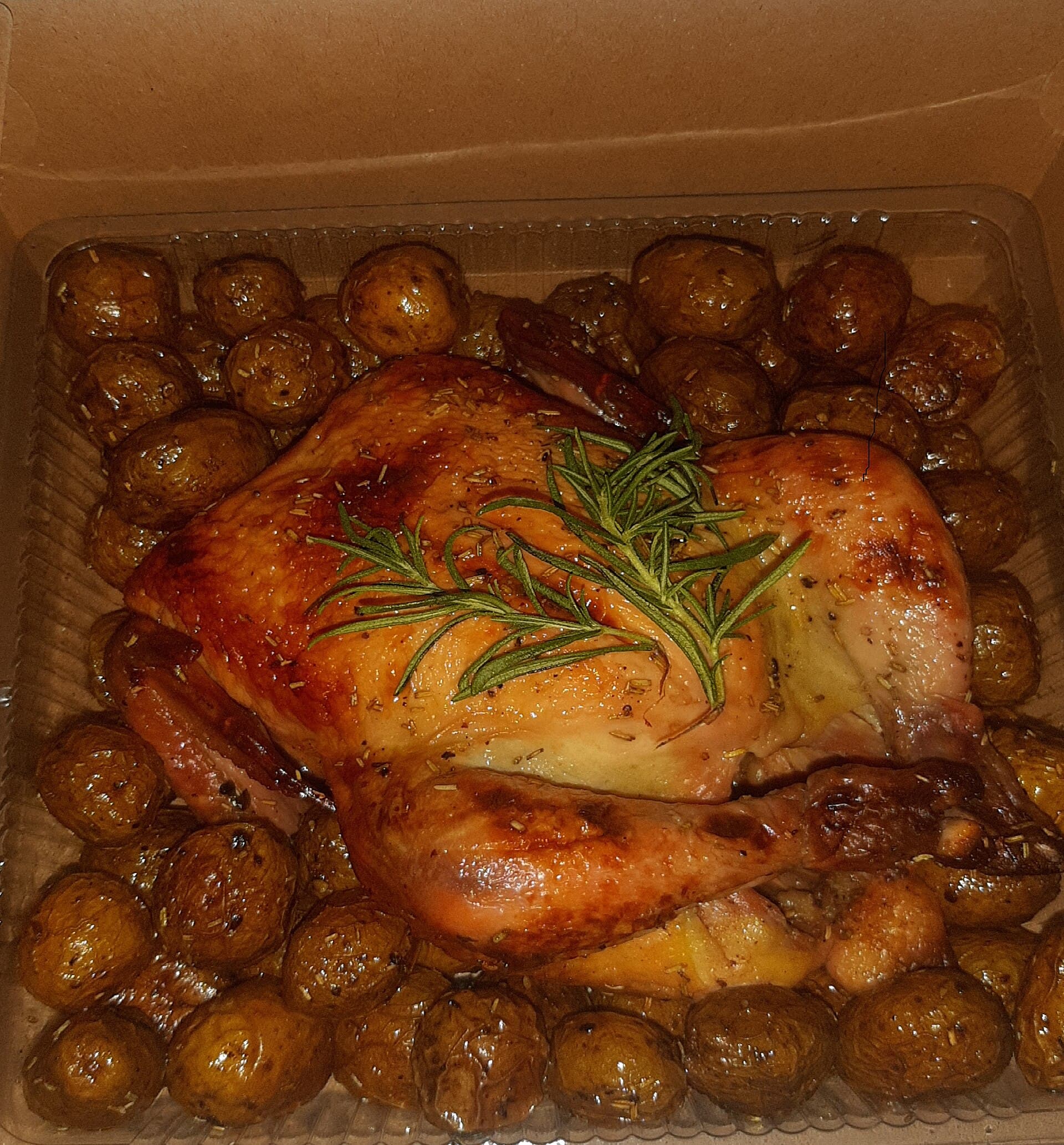A golden roast chicken served on a plate with roasted potato